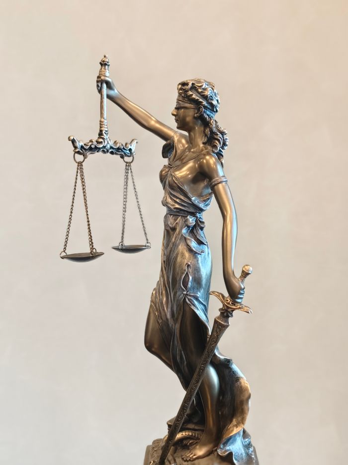 Bronze statue of Lady Justice balancing scales and holding a sword, symbolizing law and order.