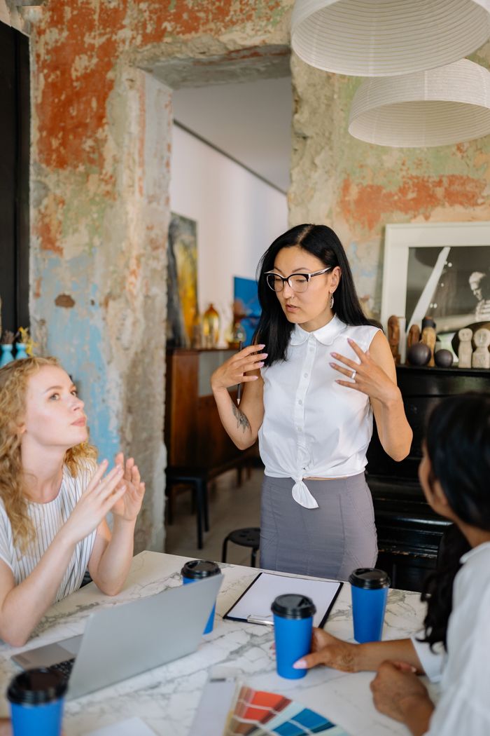 Three diverse women brainstorming in a creative workspace with laptops and coffee.